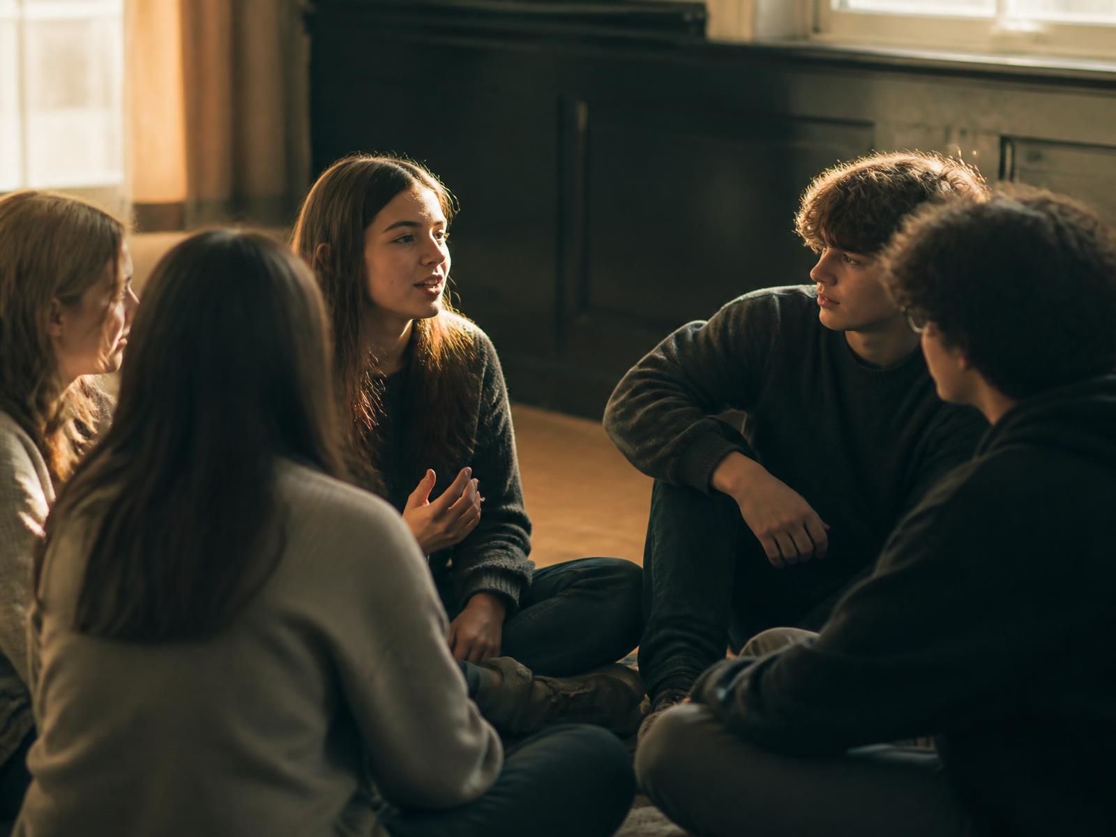 A circle of students sitting together, listening as one of them speaks